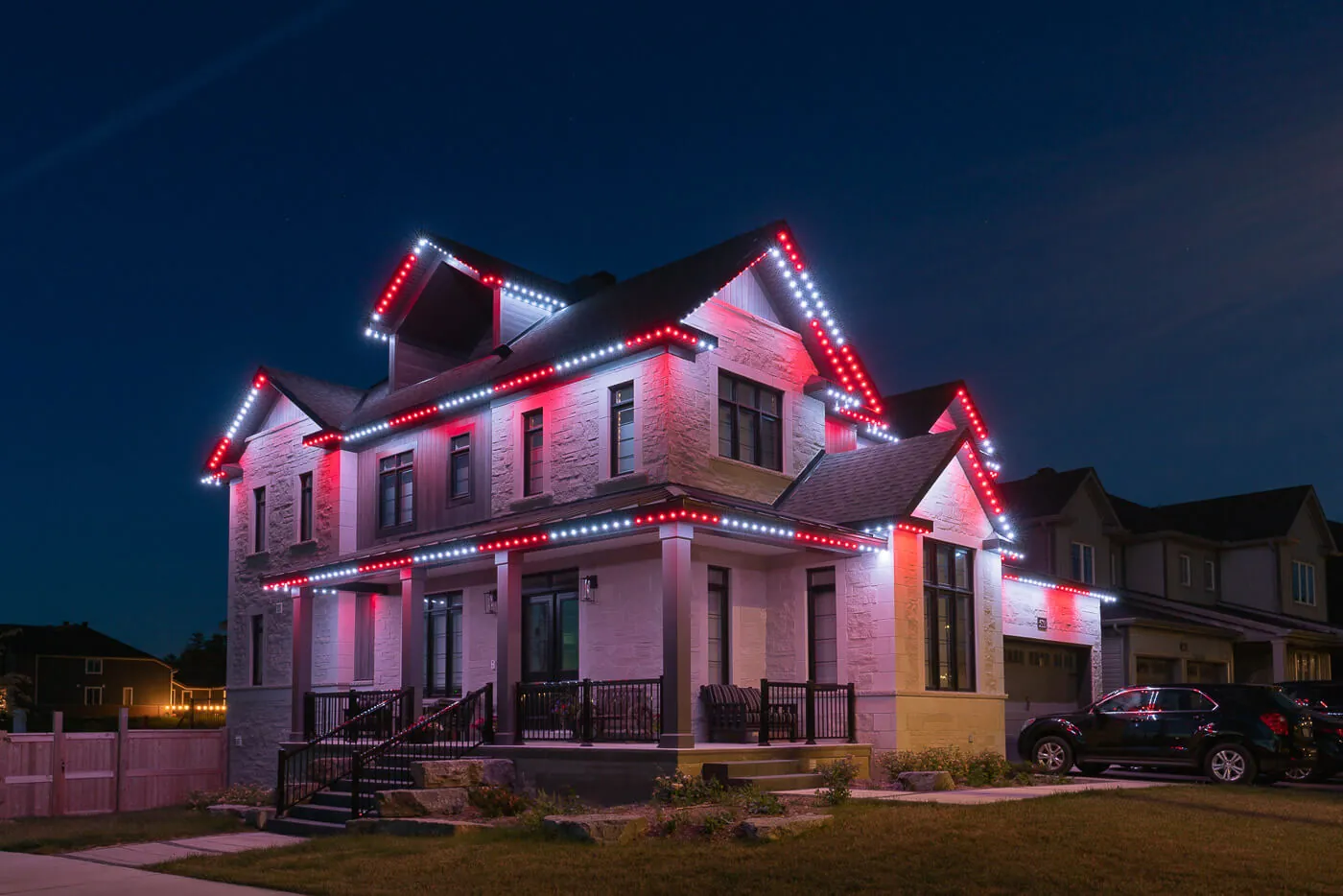 Celebright red-and-white lighting along the roofline of a two-story home