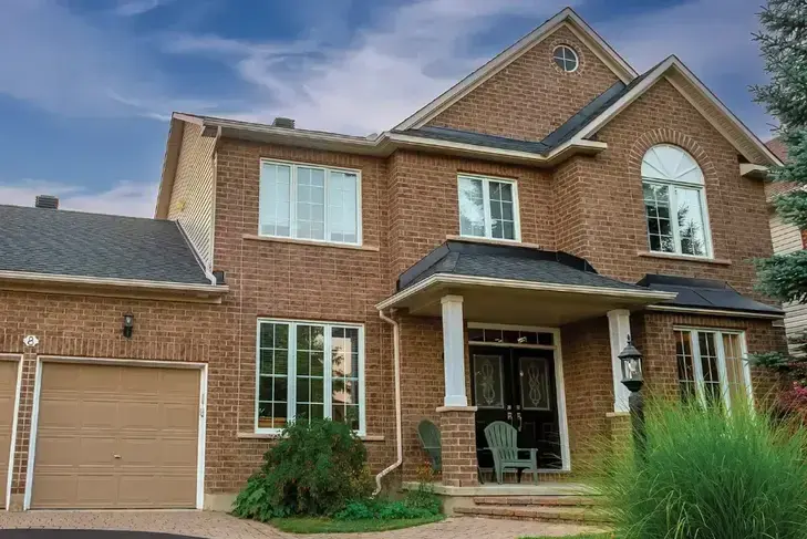 The same brick home during the day with lighting tucked under the roofline