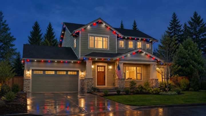 The same home at dusk with its roofline lit in red and white for a game night